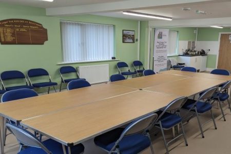 Hwb Rhuddlan room set up with tables and kitchen area visible